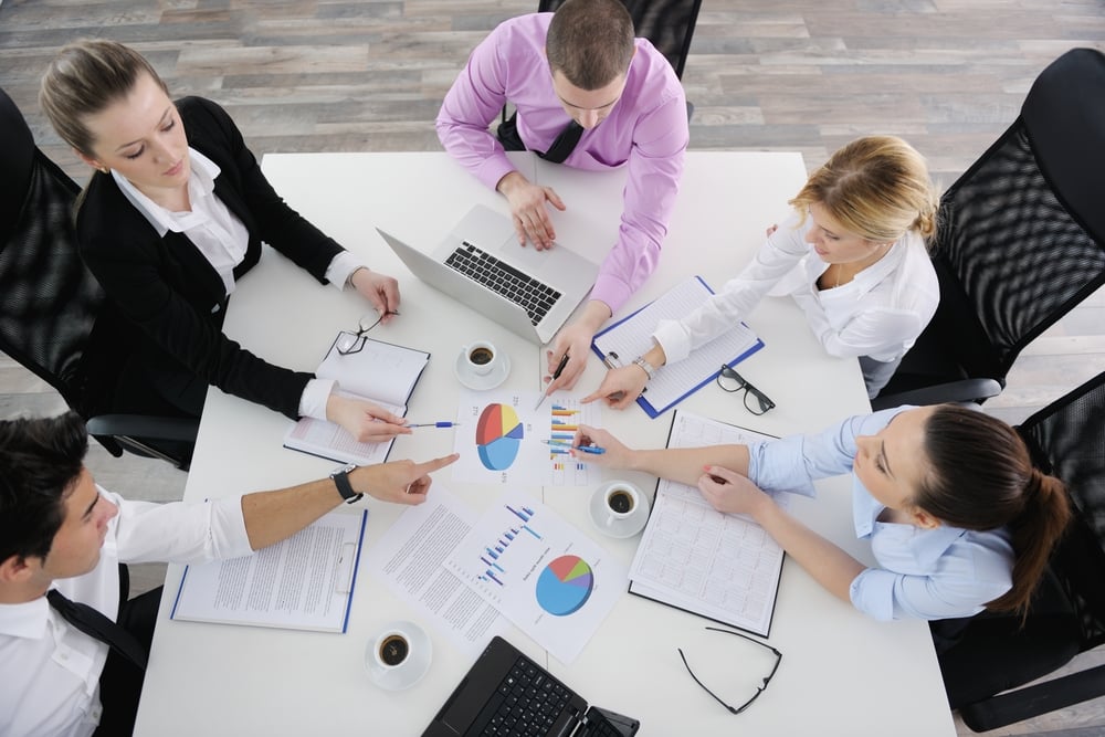 Group of young business people sitting in board room during meeting and discussing with paperwork-1